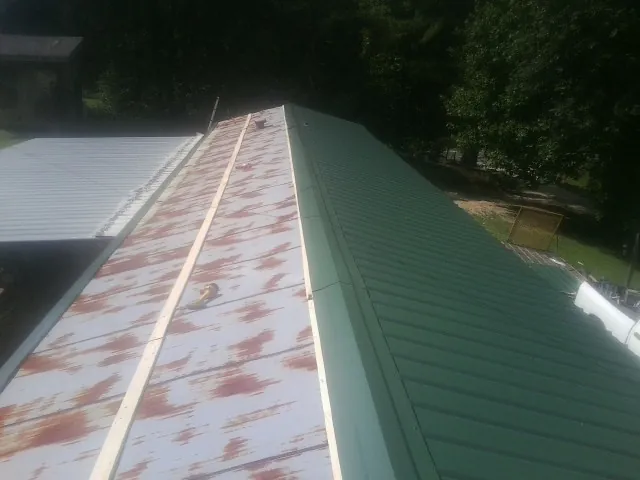 Old rusted panels beside newly installed green metal roofing — Wind Damage Roof Repair by Roofing Brothers in Cullman