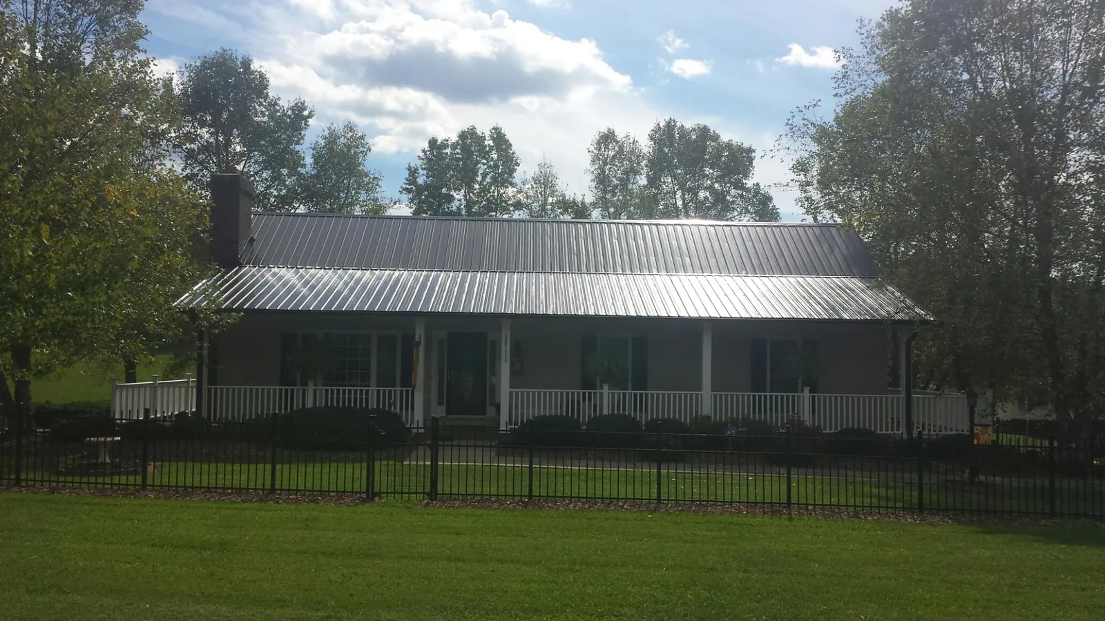 Gray metal roof on a brick ranch with a full width front porch — Gutter Guard Installation work by our crew in Cullman